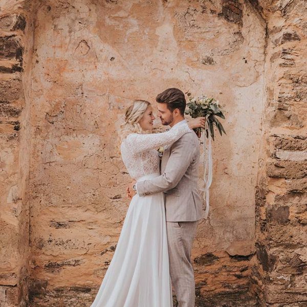 Brautpaar in weißem Brautkleid und beigen Anzug