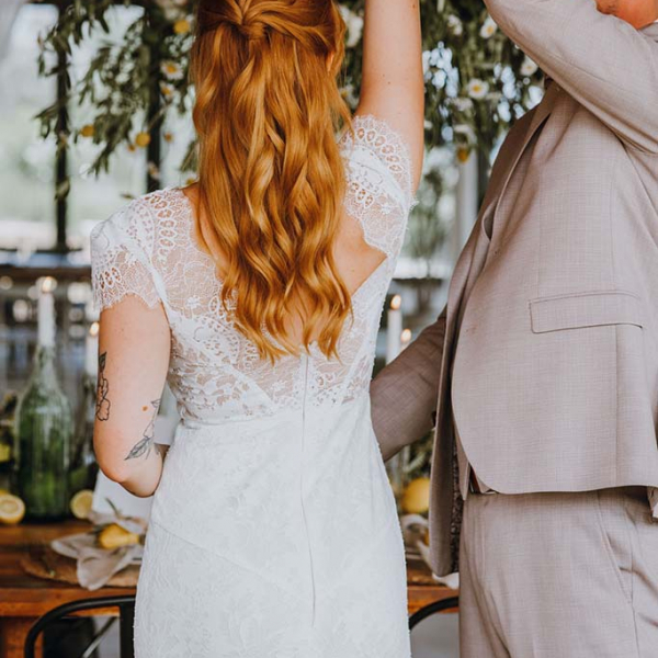 Braut mit eng anliegenden Brautkleid und Bräutigam in hellen Anzug